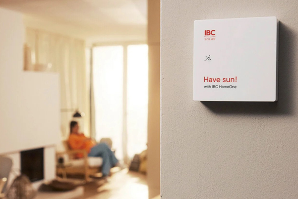 Aufnahme eines Wohnzimmers unscharf im Hintergrund; Vordergrund zeigt beige Wand mit angebrachtem Energiemanagement System mit Schrift "Have sun!"